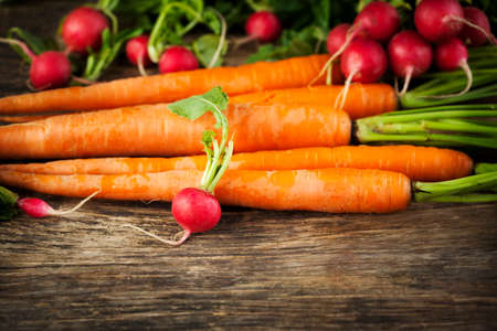 Fresh carrots and radish on wooden background. Selective focus.の写真素材