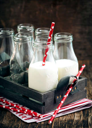 Crate of milk bottles with drinking straws in rustic styleの写真素材