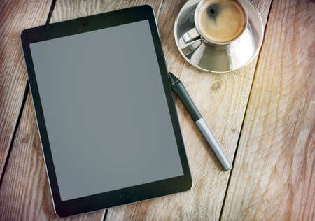 Cup of coffee and tablet on wooden tableの写真素材