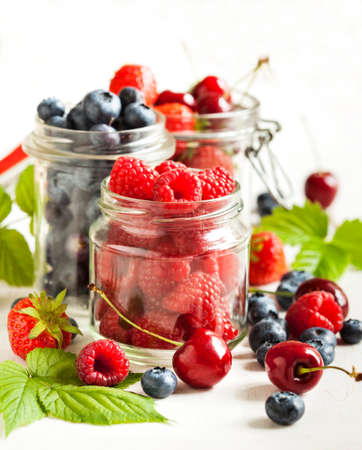 Summer berries in glass jarの写真素材