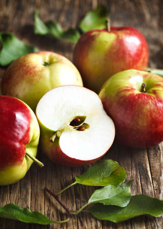 Fresh organic apples with leaves on wooden backgroundの写真素材