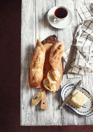 Bread with butter and cup of tea on wooden table. Top view