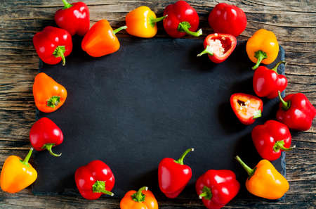 Mini Bell Peppers on wooden background with black board, top view.の写真素材