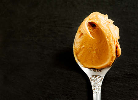 Peanut butter in spoon over black background