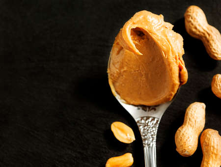Peanut butter in spoon over black background