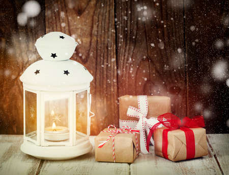 Christmas gifts and candle on wooden background