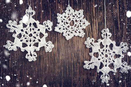 Crocheted white snow flakes on wooden backgroundの写真素材