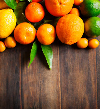Fresh citrus fruits with leaves on wooden backgroundの写真素材