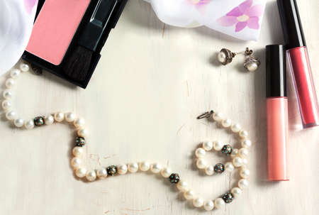 Women's set of fashion accessories on wooden background: pearl neclace, earrings, lipstick, blush and scarfの写真素材