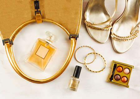 Women's set of fashion accessories in golden color on wooden background: shoes, handbag, perfume and cosmeticsの写真素材