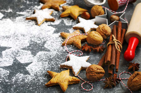 Christmas cookies, roller pin, cinnamon, nuts and cookie cutter on dark backgroundの写真素材