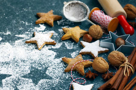 Christmas cookies, roller pin, cinnamon, nuts and cookie cutter on dark backgroundの写真素材
