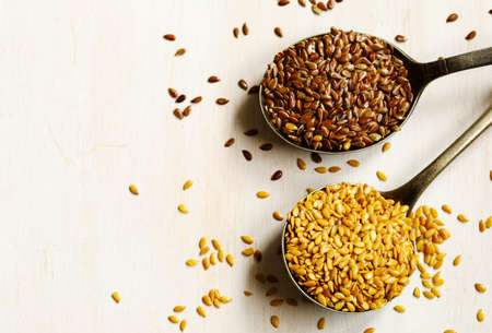 Brown and golden flax seeds in spoonsの写真素材