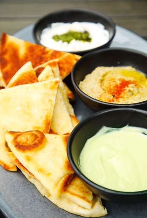 Grilled flatbread with spreads: creamy avocado, chickpea hummus and whipped ricottaの写真素材