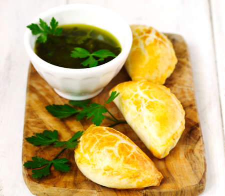 Empanadas with chimichurri sauce on wooden tableの写真素材