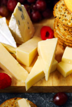 Cheese, creckers and fruits on wooden backgroundの写真素材