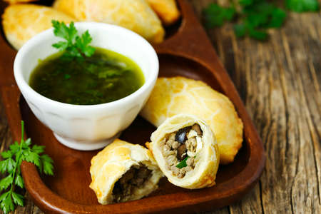 Empanadas with chimichurri sauce on wooden tableの写真素材