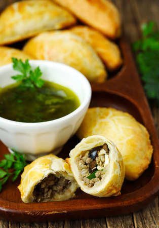 Empanadas with chimichurri sauce on wooden tableの写真素材