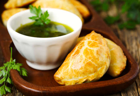 Empanadas with chimichurri sauce on wooden tableの写真素材