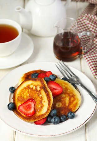 Pancakes with strawberries, blueberries and maple syrup for a breakfast.の写真素材