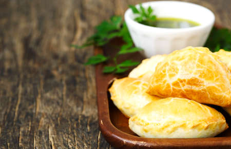 Empanadas with chimichurri sauce on wooden table