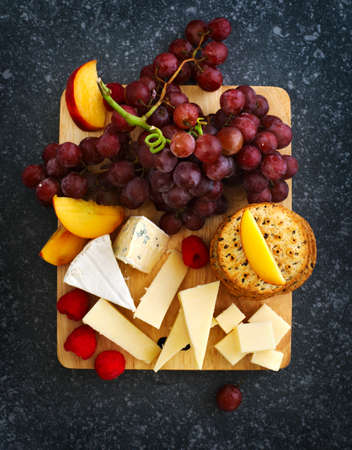 Cheese, creckers and fruits on wooden backgroundの写真素材