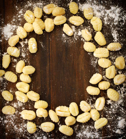 Uncooked homemade potato gnocchi on wooden background, top view, frameの写真素材
