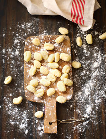 Uncooked homemade potato gnocchi on wooden background, top viewの写真素材