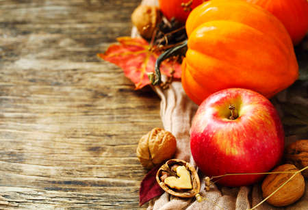 Autumn pumpkins and apples with fall leaves on wooden background with copy space. Autumn compositionの写真素材