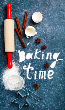 Baking time. Flour sprinkled on the blue table with text baking time. Baking ingredients.の写真素材