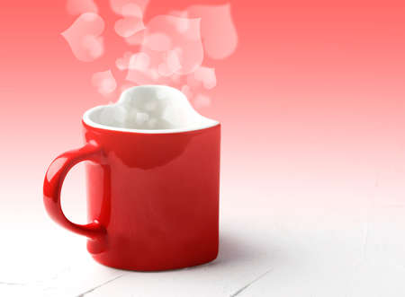 Red mug in shape of heart on white table at light red background with bokeh, front view. Valentine day concept background, copy space.の写真素材