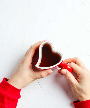 Female hand holding cup of tea in shape of heart on white background, top viewの写真素材