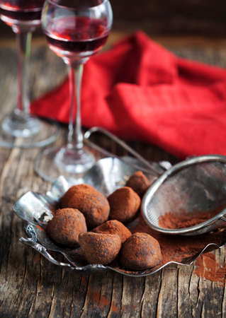 Dark chocolate truffles and two glasses of raspberry  liqueurの写真素材