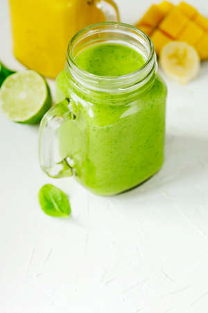 Green Spinach Avocado Smoothie and Banana Mango Smoothie in mason jars. Healthy vegan eating.の写真素材