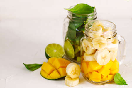 Ingredients for Green Spinach Avocado Smoothie and Banana Mango Smoothie in mason jars. Healthy vegan eating.の写真素材