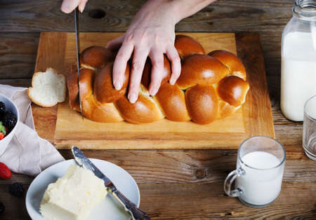 The woman cuts bread on wooden boardの写真素材