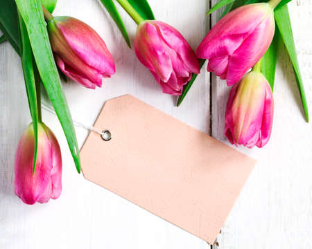 Spring tulips with tags on white wooden background, top viewの写真素材