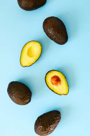 Avocado halves and whole on a blue speckle, top viev.の写真素材