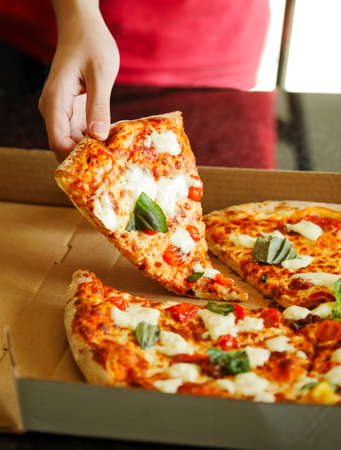 Person's hand taking slices of pizza.の写真素材