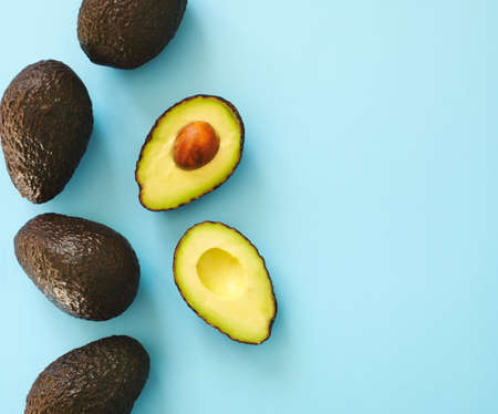 Avocado halves and whole on a blue speckle, top viev.の写真素材