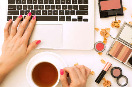 Woman holding tea mug in hand and working on laptop. Fashion blogger concept, flat lay, top viewの写真素材