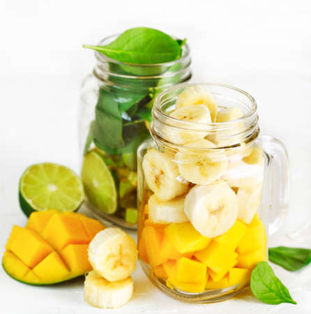 Ingredients for Green Spinach Avocado Smoothie and Banana Mango Smoothie in mason jars. Healthy vegan eating.の写真素材