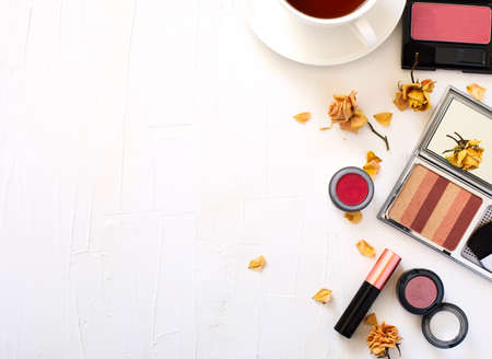 Flat lay with cup of tea and woman make up products on white backgroundの写真素材