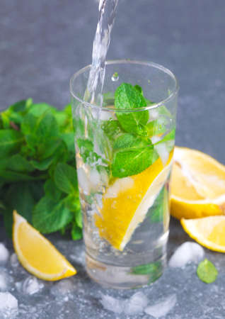 Glass of aced water with lemon and mint. Water drink pouring into glassの写真素材