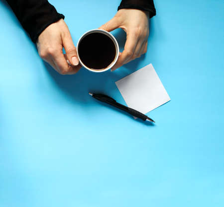 Woman holding coffee mug in hand on blue background, top vew, copy spaceの写真素材