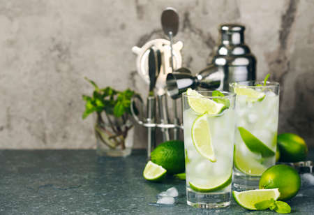 Mojito cocktail with lime and mint in glass on a stone table. Bar tools and ingredients for cocktail.の写真素材