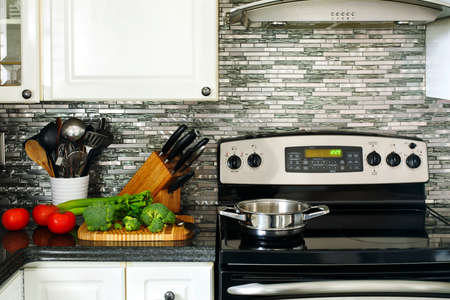 Electric Stainless steel stove, kitchen utensils and vegetables on the cooking tableの写真素材