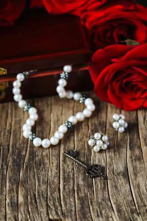 Fresh red roses with pearls on wooden background, copy space