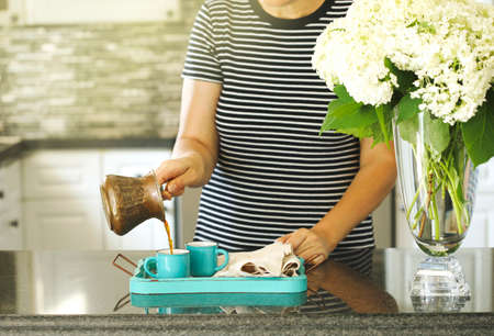 A woman is pouring coffee in a cupsの写真素材