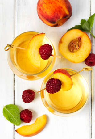 Peach wine and fruits on white wooden table, top viewの写真素材